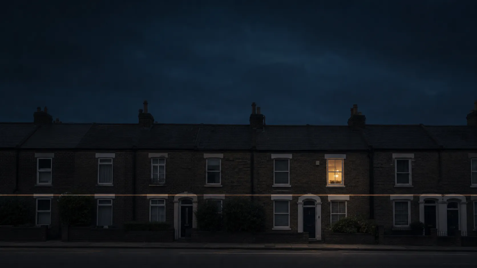 A terrace of houses at dusk, one warmly lit window